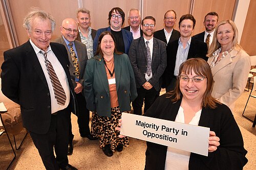 Liberal Democrat councillors holding a sign stating 'Majority Party in Opposition'